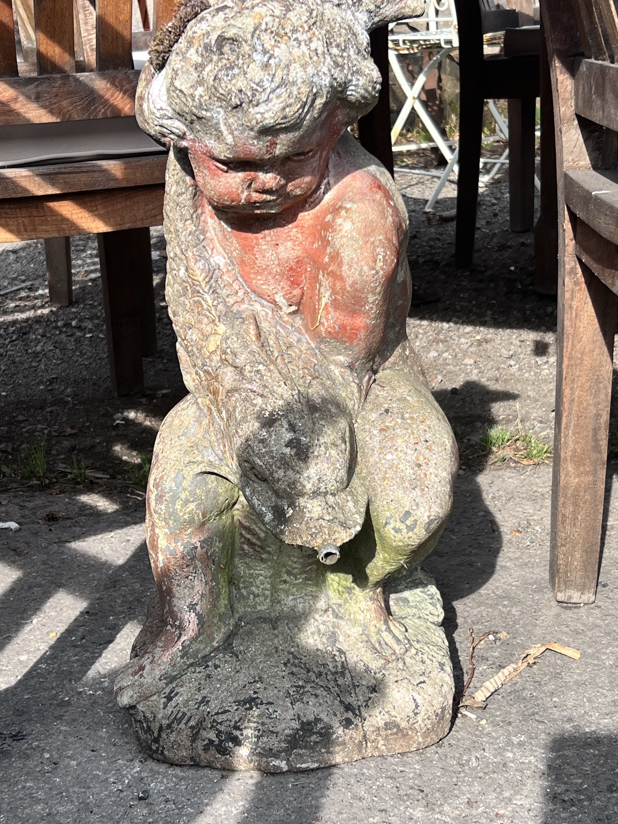 A reconstituted stone garden fountain modelled as a figure of a cherub holding a dolphin, height 69cm